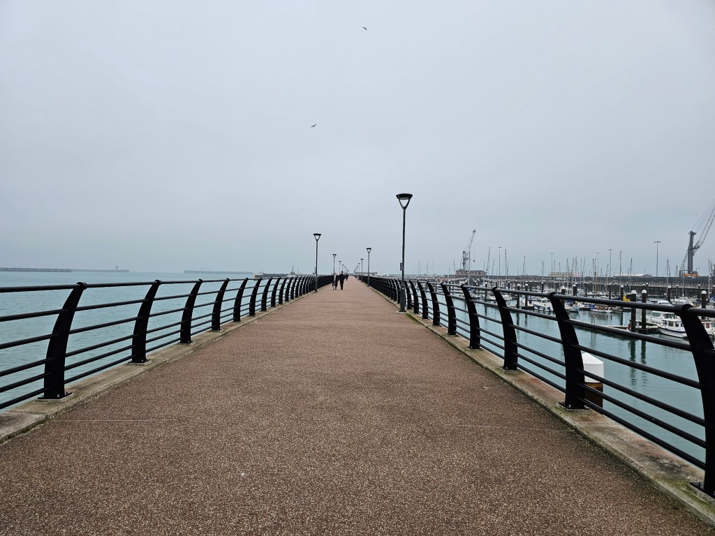 A photo of Dover pier - a long path with black metal railing on both sides.