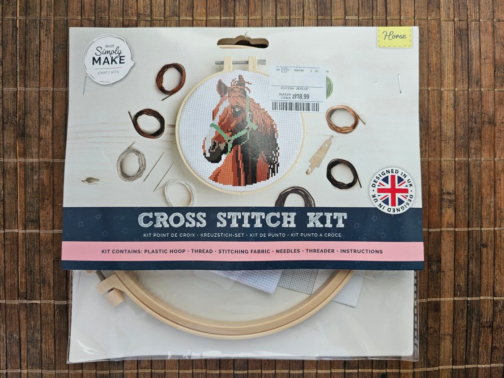 The packaging of a cross stitch set with a horse design. It includes an embroidery hoop, embroidery thread, a needle, a threader, and instructions