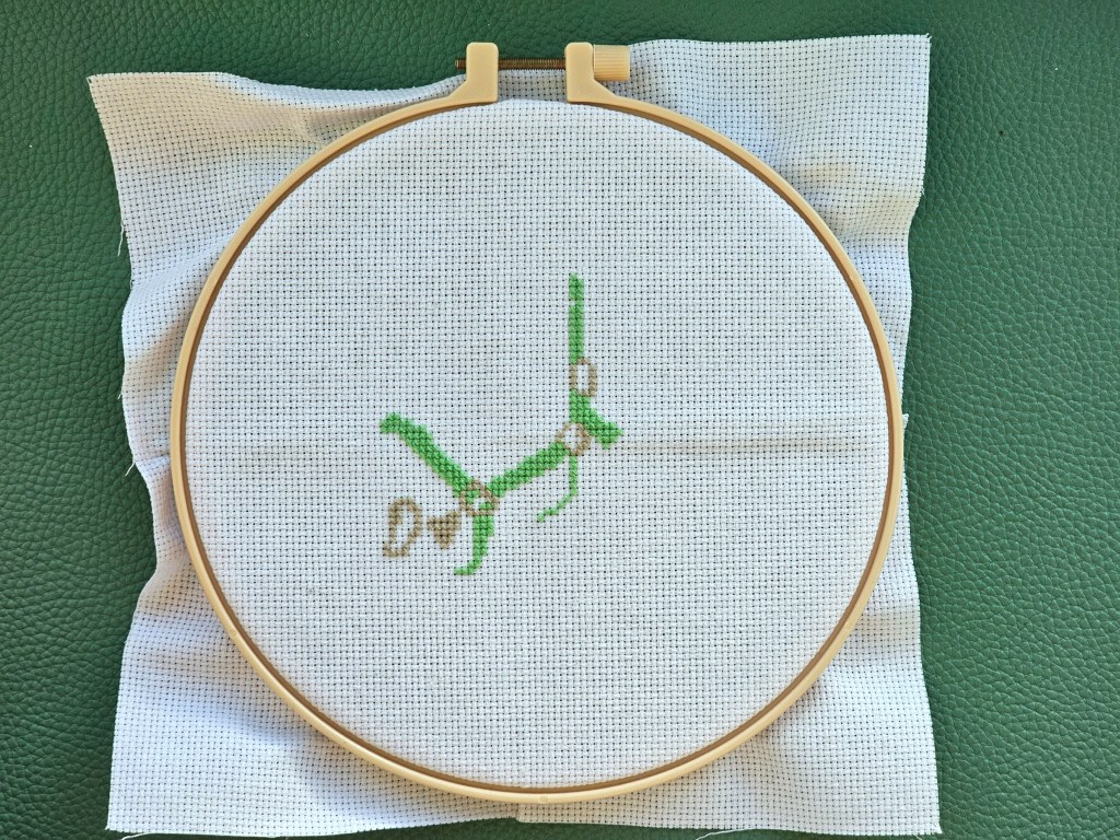 Partially completed cross stitch project featuring a horse. Teal and grey elements are finished. Brown parts are left to sew.