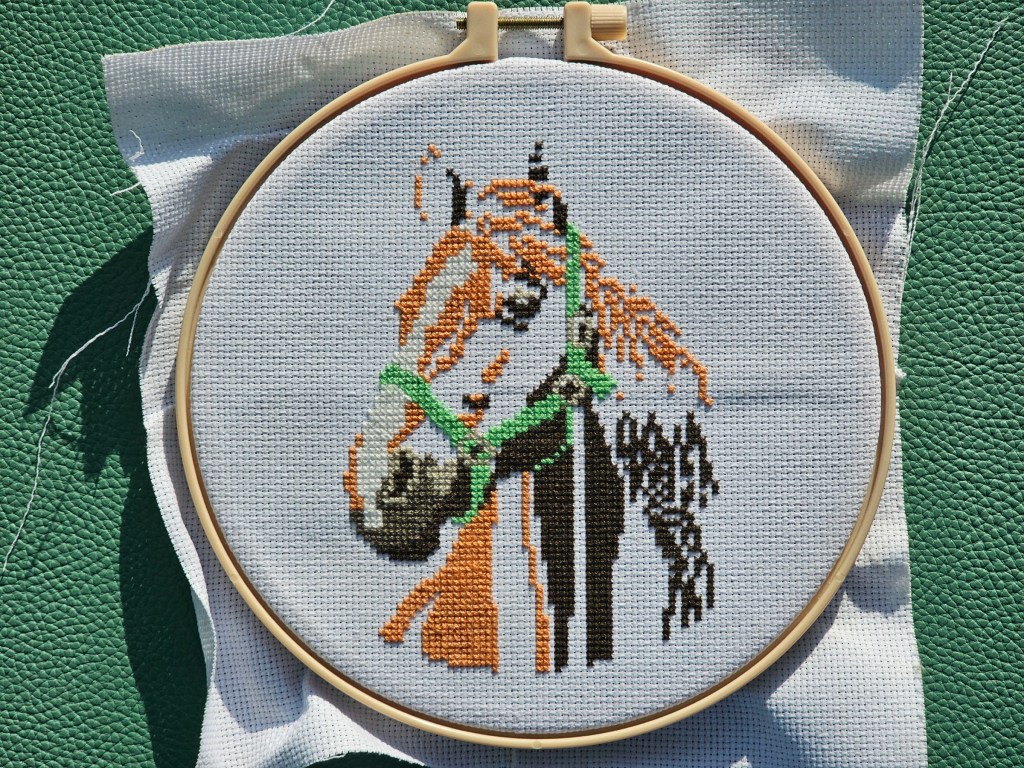 Nearly completed cross stitch project featuring a realistic horse. Only two colours are left to sew