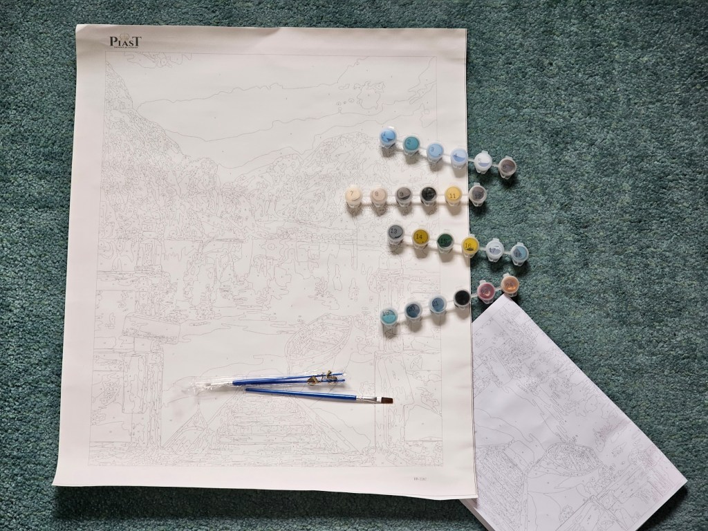 Contents of a painting by numbers set. It includes a canvas with the printed pattern, 24 small paint pots and three brushes.