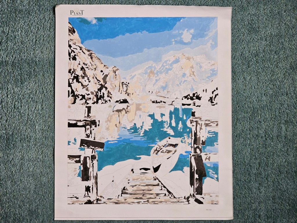 Half completed painting by numbers project depicting a lake in the mountains.