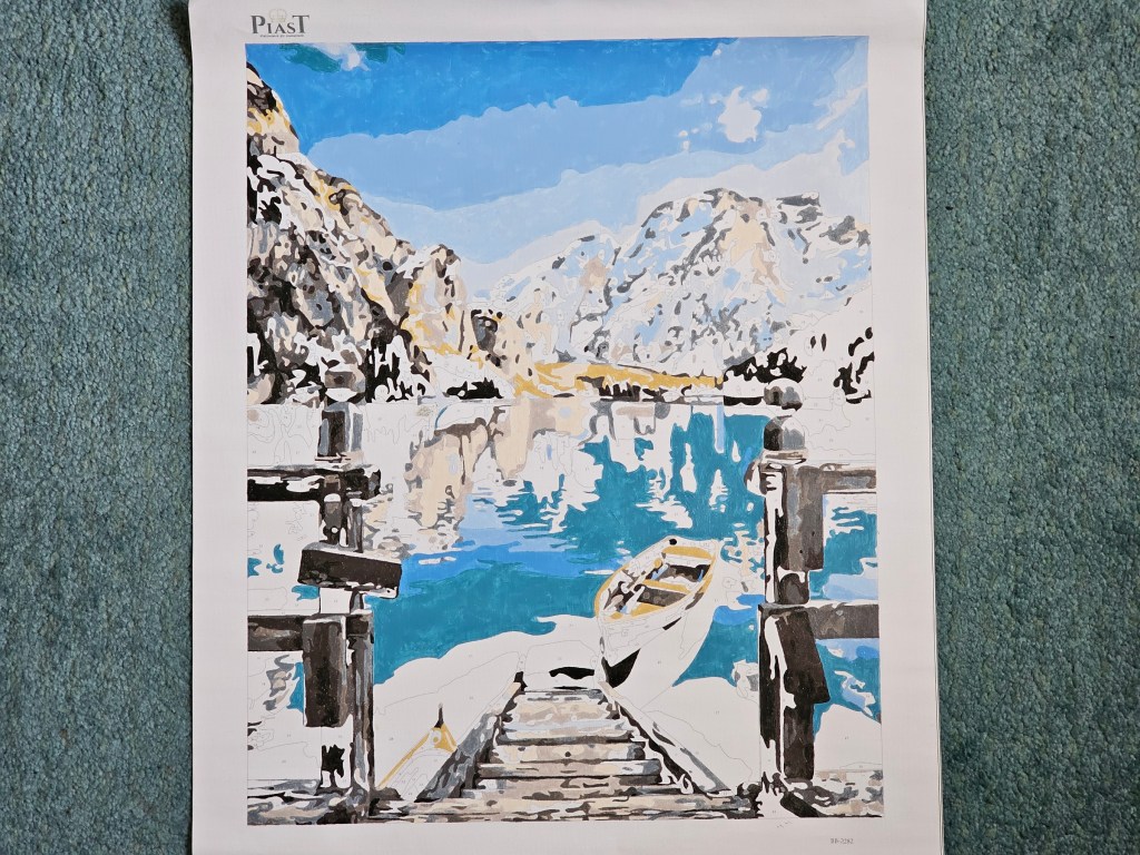 Half completed painting by numbers project depicting a lake in the mountains.