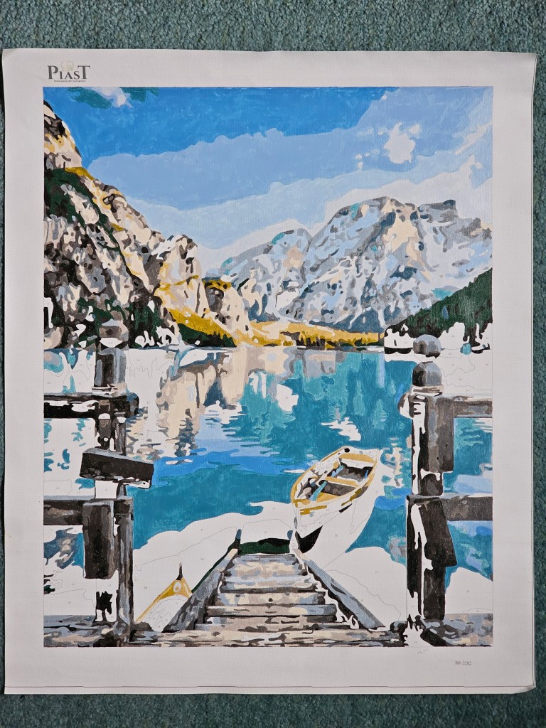 Nearly finished painting by numbers project depicting a lake in the mountains.