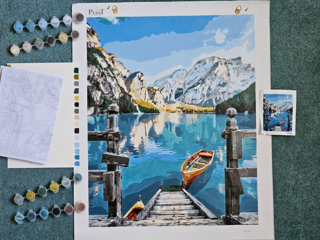 Finished painting by numbers project depicting a lake in the mountains.