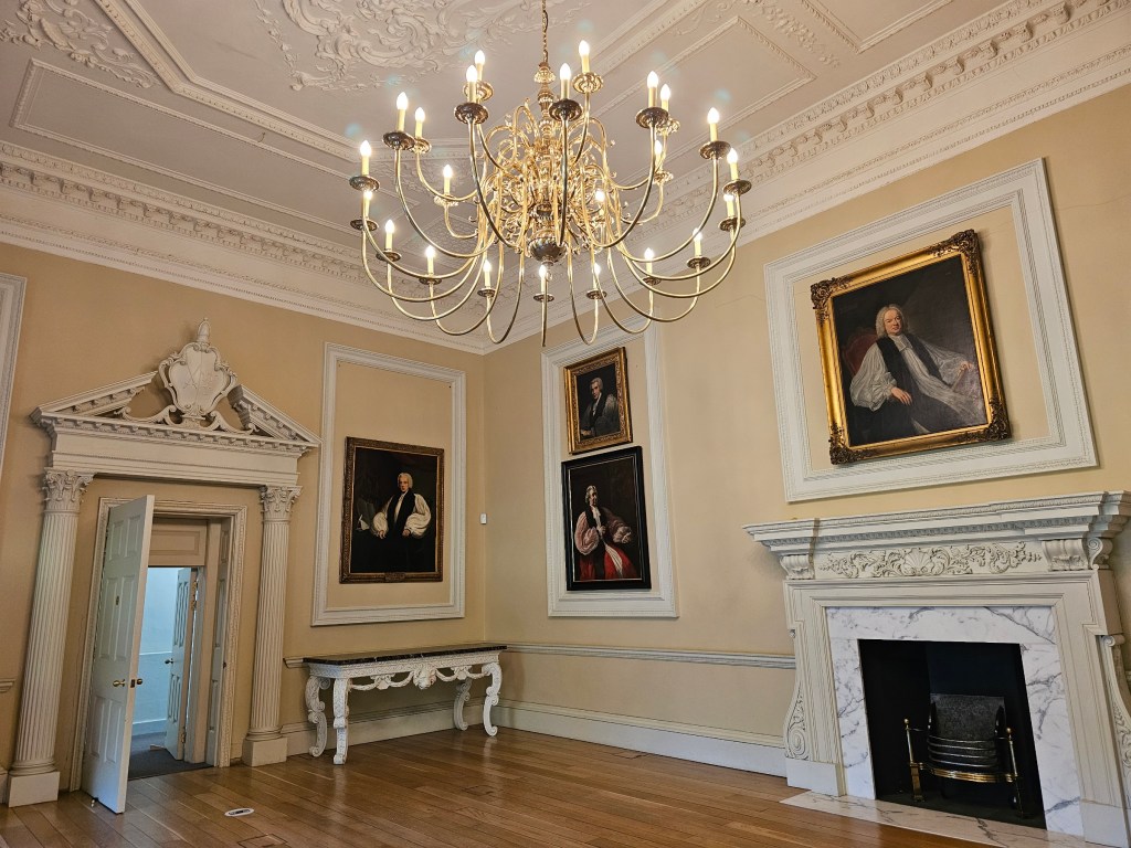 State room in Fulham Palace. There's a fancy chandelier, and painted portraits on the walls
