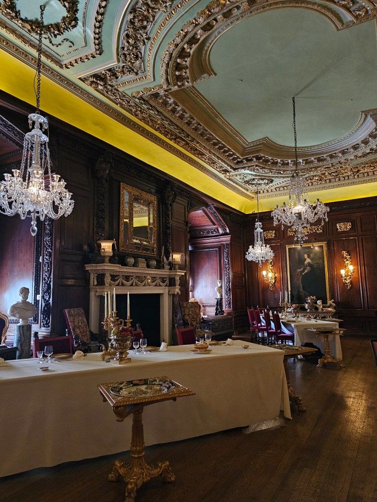 Dining room of Warwick Castle, England. There are crystal chandeliers hanging above the tables.
