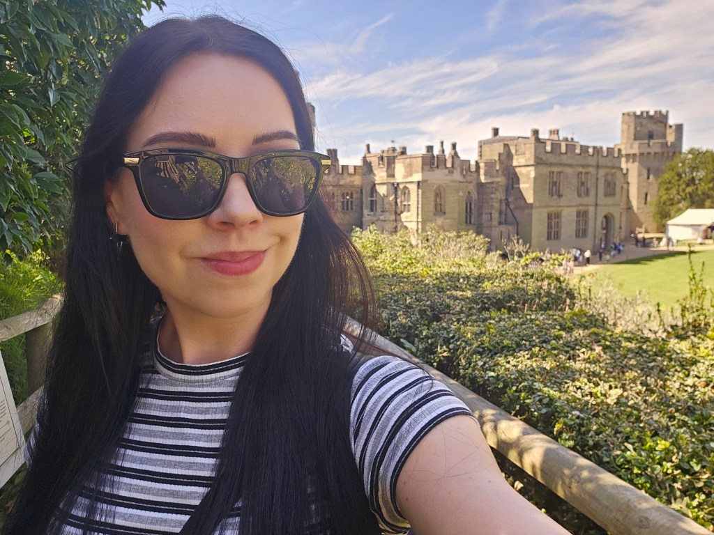 A selfie of a woman with Warwick Castle in the background