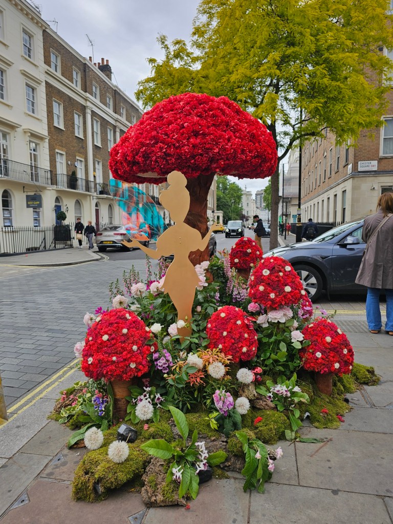 A floral display featuring colourful mushrooms and a silhouette of Tinkerbell. Photo taken during Belgravia in Bloom 2026 in London