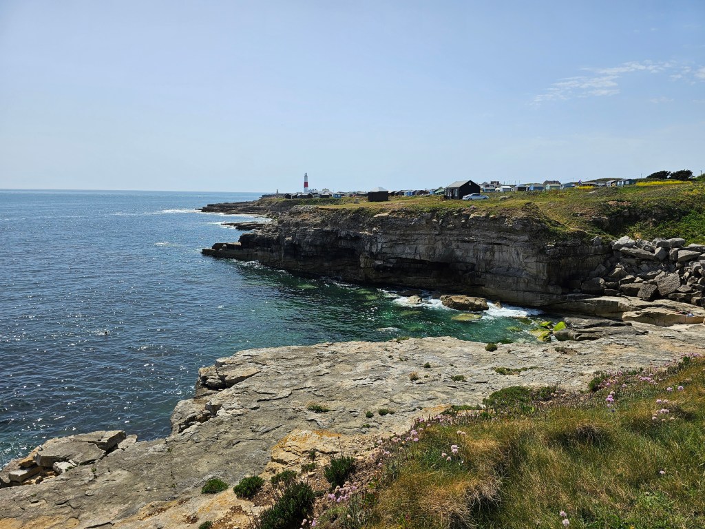 Rocky coastal path on the Isle of Portland, Dorset, UK. Portland Bill lighthouse can be seen on the horizon