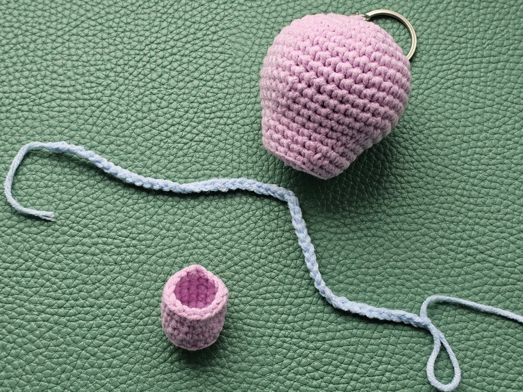 Crocheted pink balloon, tiny basket, and a blue chain