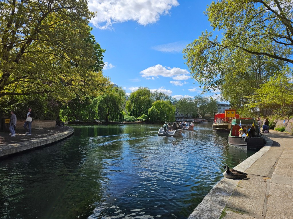 A canal in central London, with boats in the water. Photo taken during beautiful weather, with blue skies.