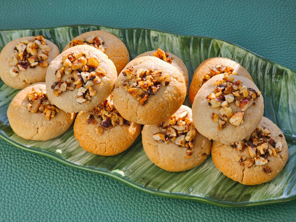 Baked tahini almond cookies topped with honey roasted nuts, on a leaf-shaped plate