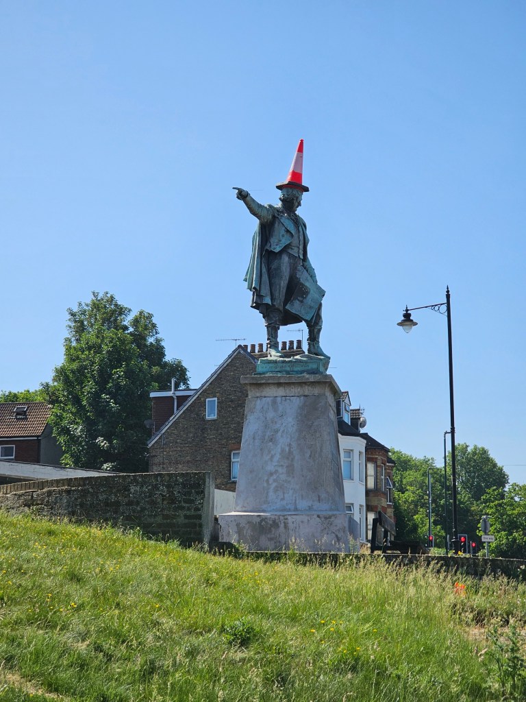 A statue of a man in Chatham, England, with a traffic cone on his head