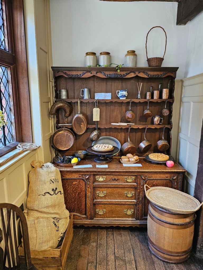 An old kitchen segment in Eastgate House, with rows of hanging copper pans and faux baked goods