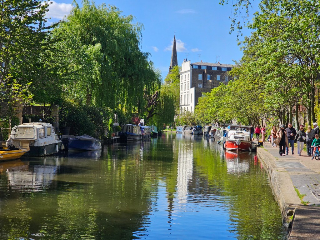 A canal with several narrowboats along a footpath in London