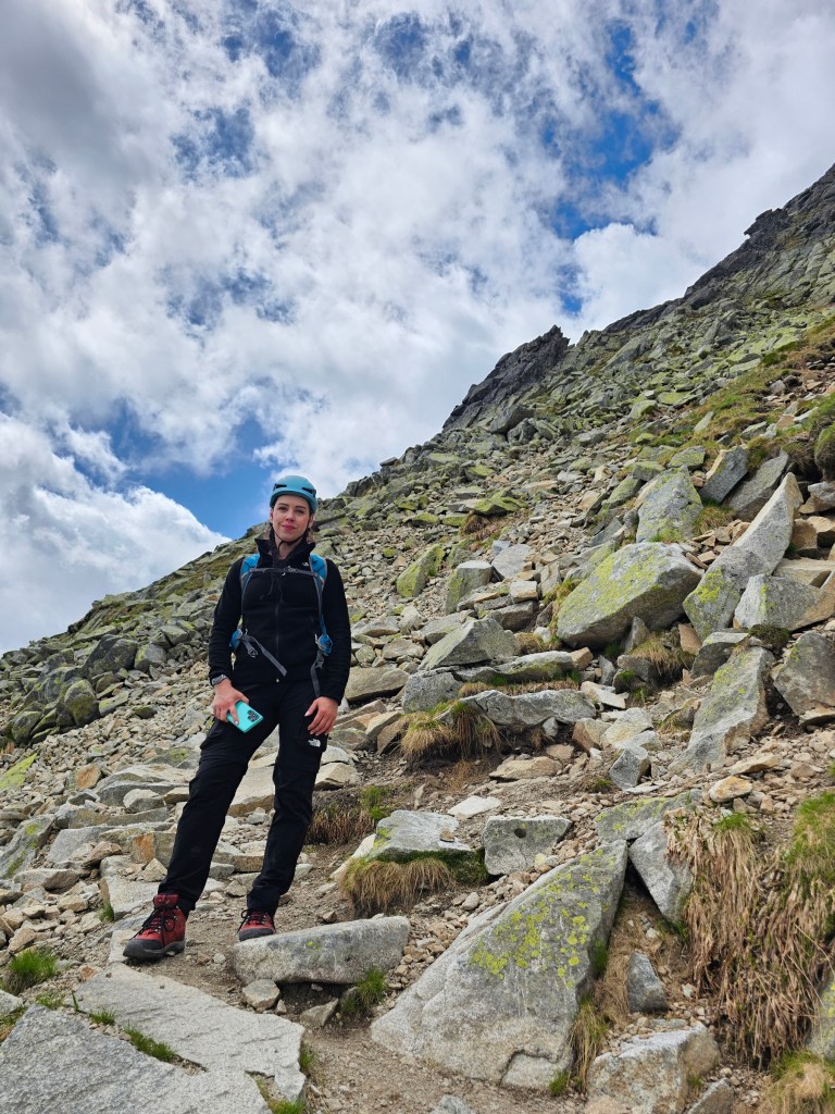A person wearing hiking gear, standing on the side of a rocky mountain