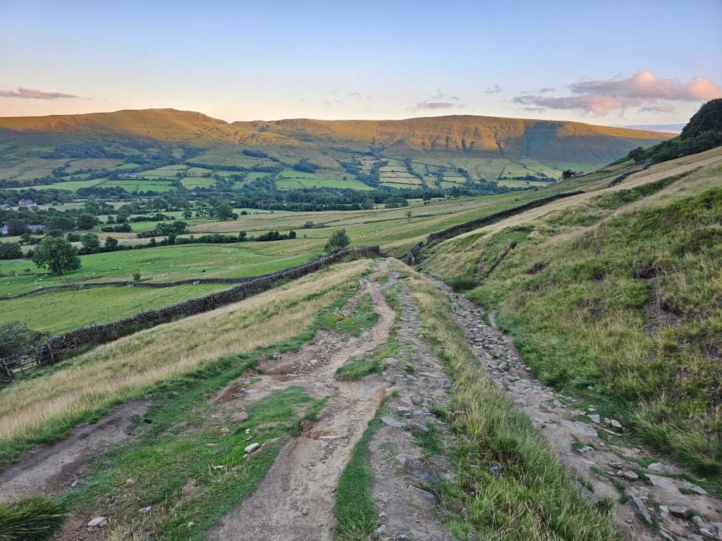 A gravel path downhill in Peak District, England. Other hills can be seen in the background. Photo taken during golden hour.