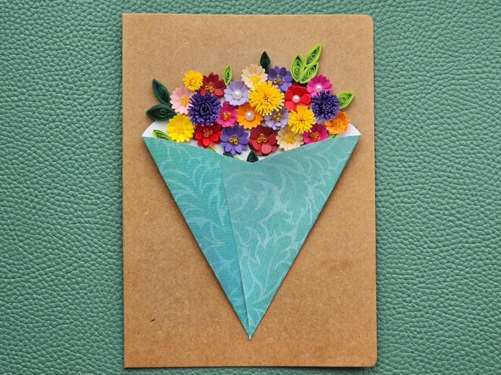 A DIY birthday card feauring a bouquet of quilled flowers in a cone