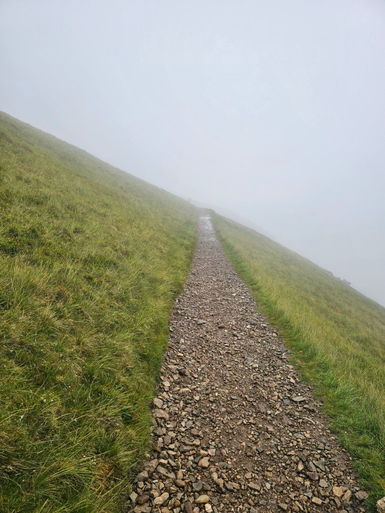 A gravel path to the top of Helvellyn. Visibility is poor, the path goes into dense fog