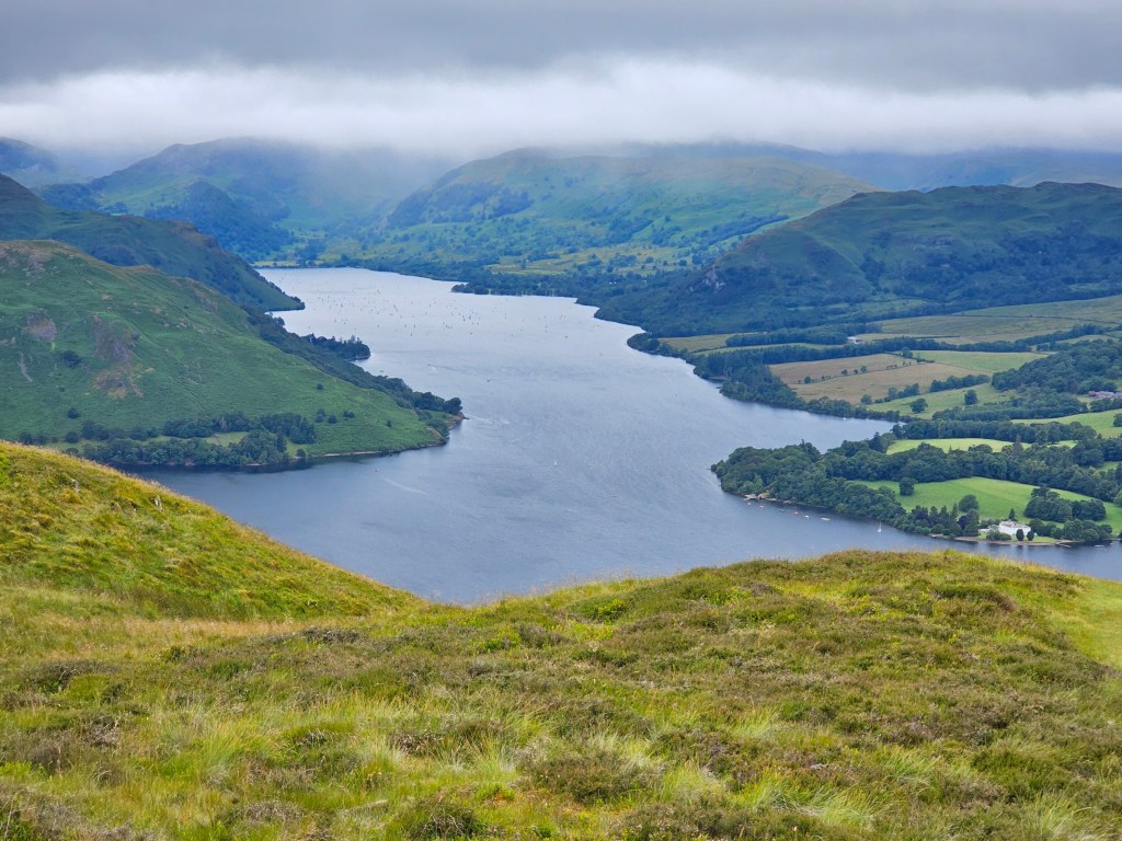 A lake and hills, seen from high up. Some peaks in the background are covered in clouds