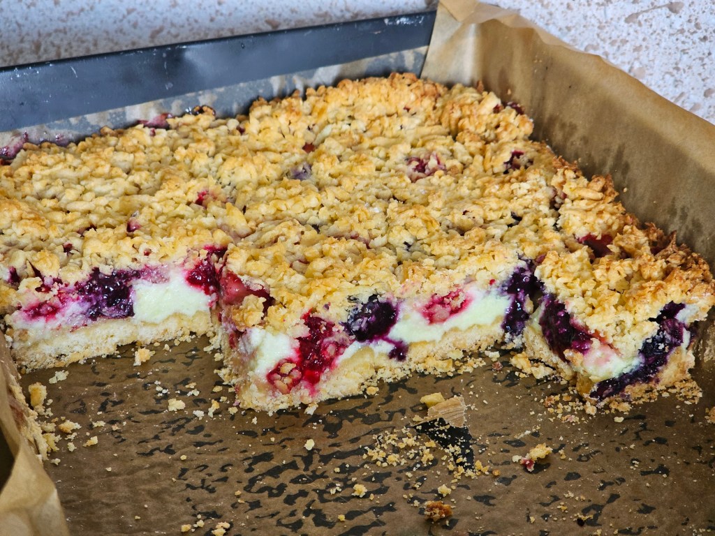 A tray with shortbread cake with a meringue layer and berries, half eaten