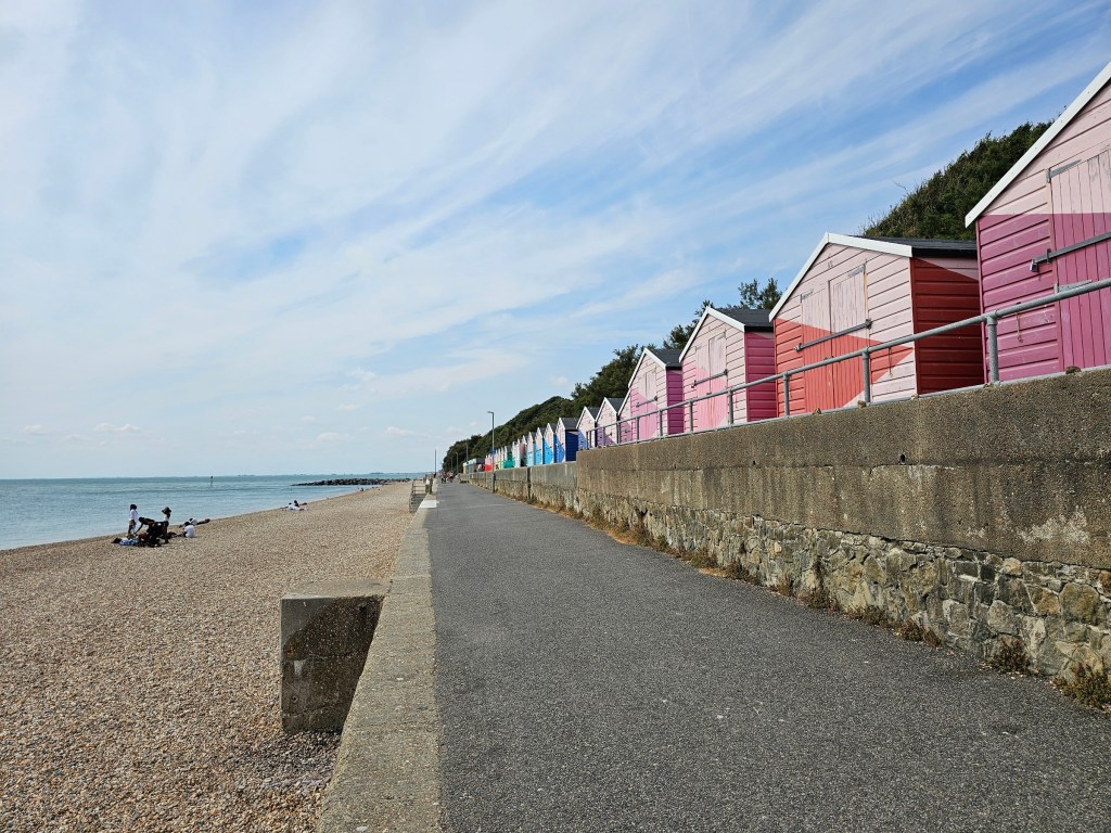 Colourful, pink beach huts along the beach in Folkestone