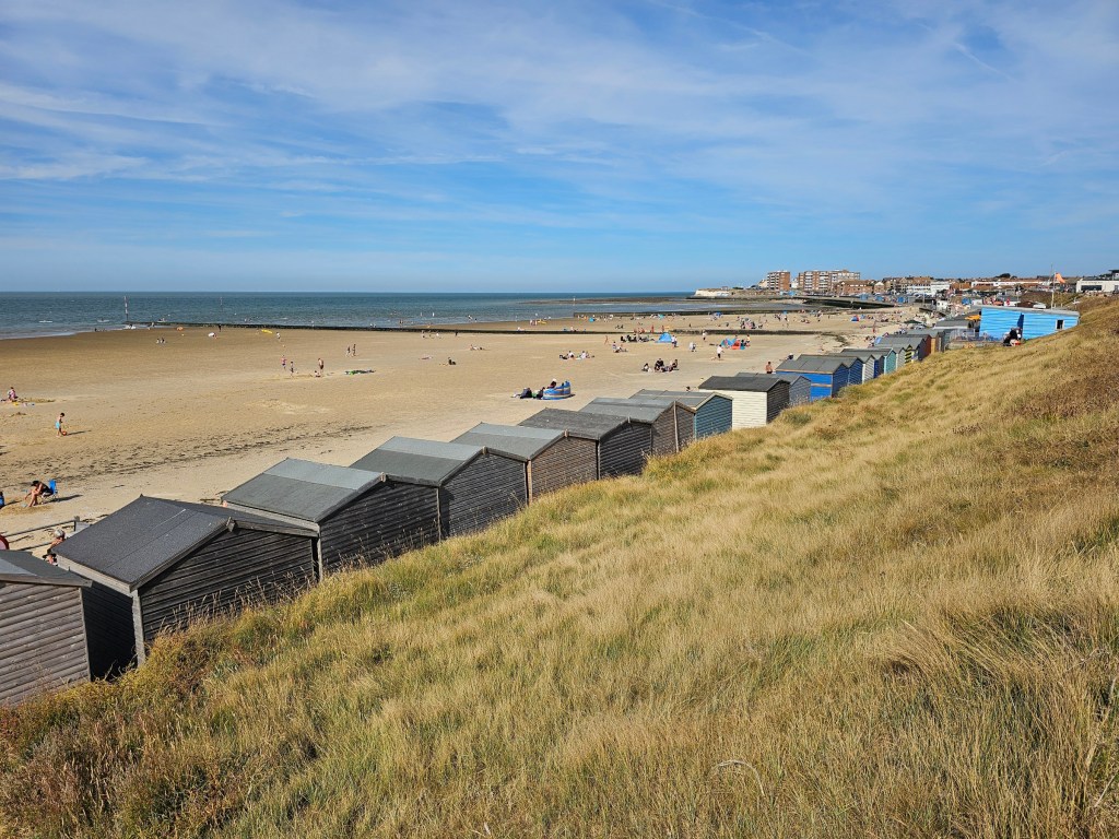 Colourful beach huts along the promenade near Margate. White sandy beach and the sea in the background