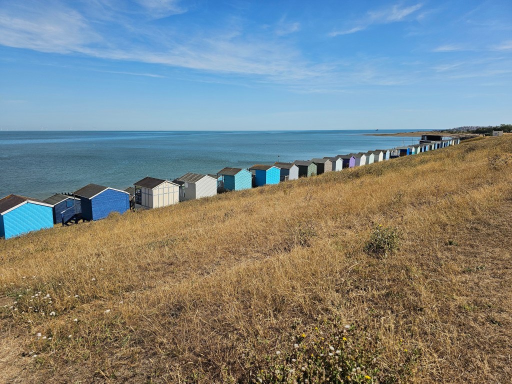 Colourful beach huts by the sea near Whitstable, seen from a hill
