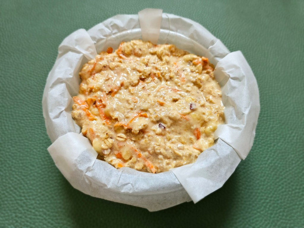 Carrot cake oats before baking, in a round ramekin lined with parchment.