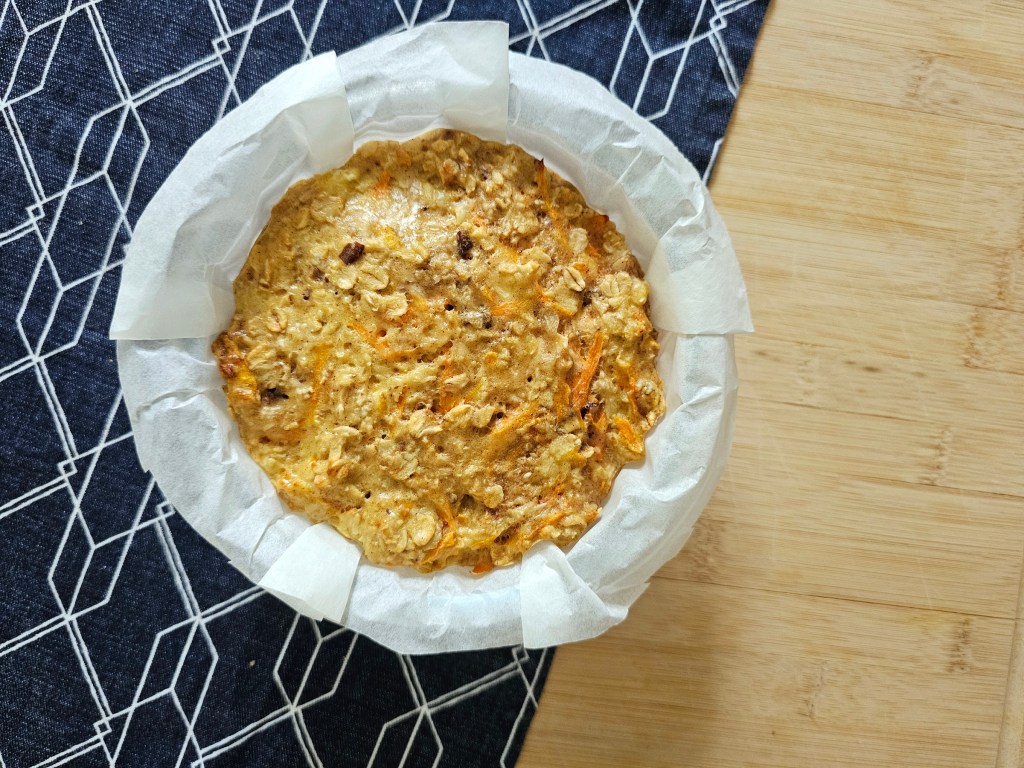 Baked carrot cake oats, in a round ramekin lined with parchment.