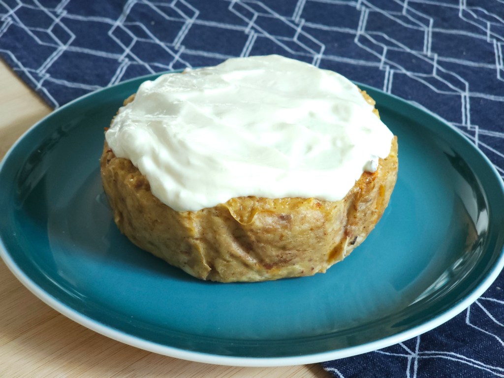 Baked carrot cake oats for one, on a plate, topped with yoghurt.