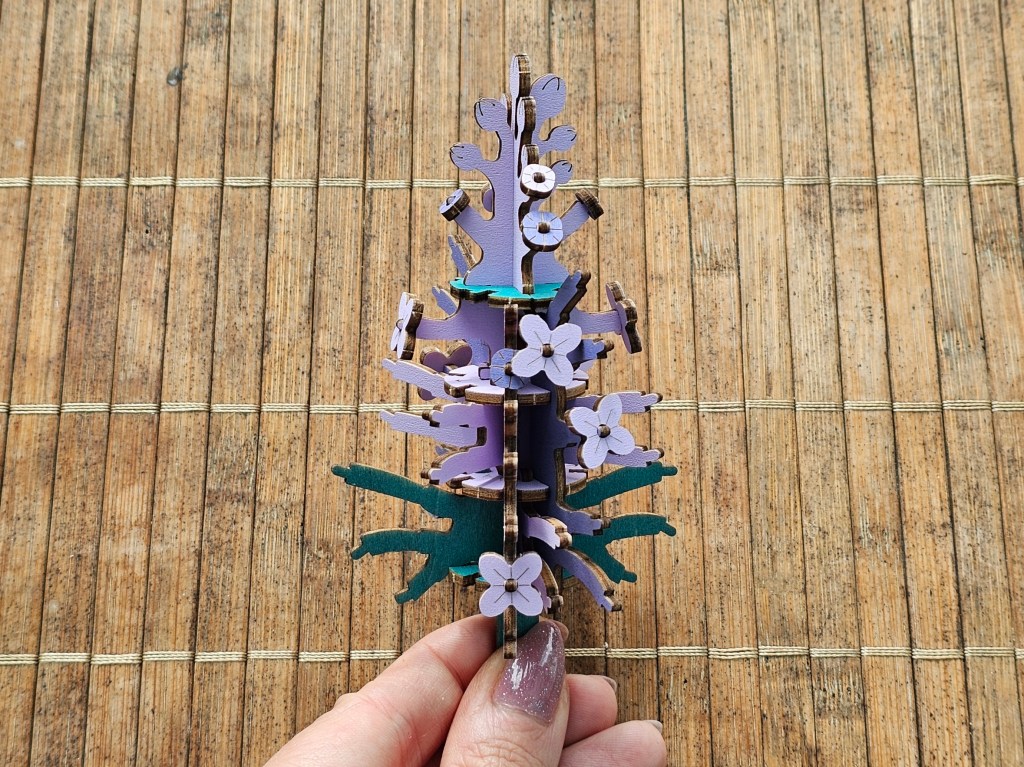 A wooden core of a lilac flower with a few small flowers attached.