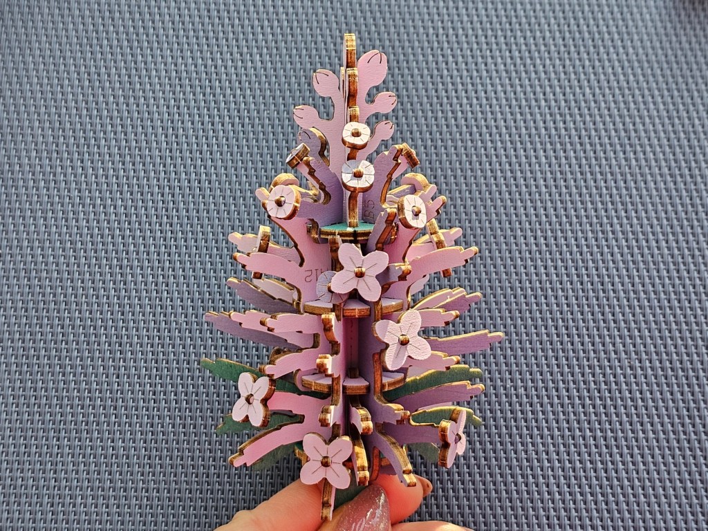 A wooden core of a lilac flower with a few small flowers attached.