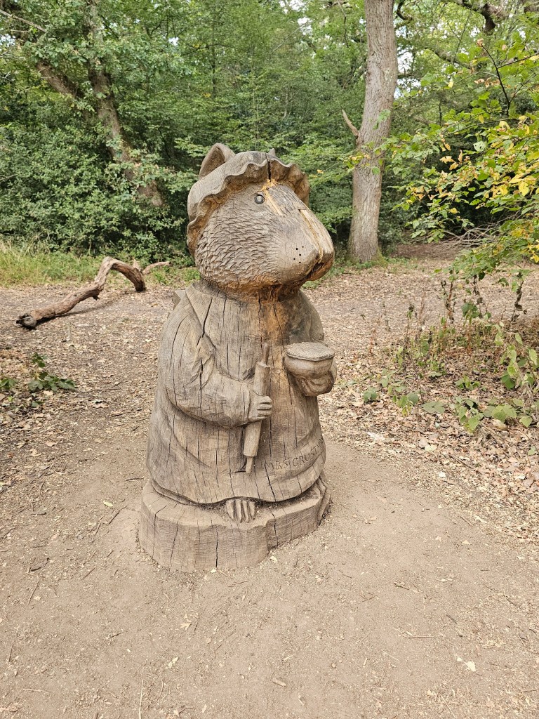 A wooden sculpture depicting a rodent holding a rolling pin