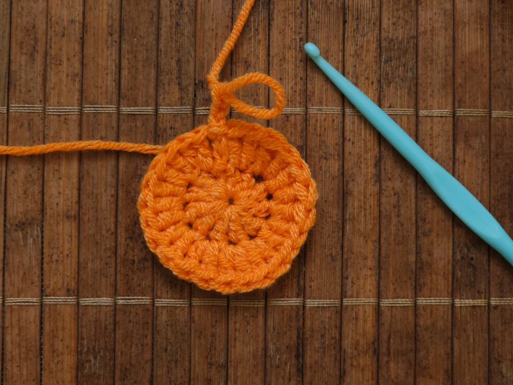 Start of an orange crocheted pumpkin coaster - magic ring with a couple of rounds of treble crochets.