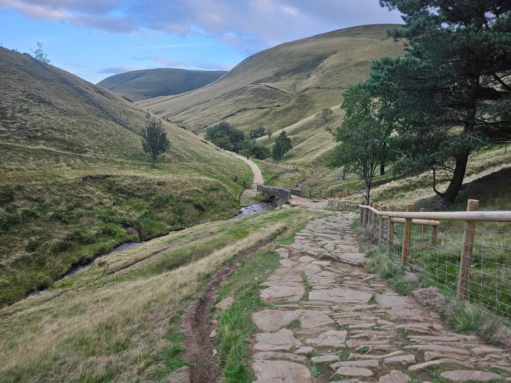 Jacob's Ladder in Peak District. A small stone bridge over a stream, with hills on both sides.