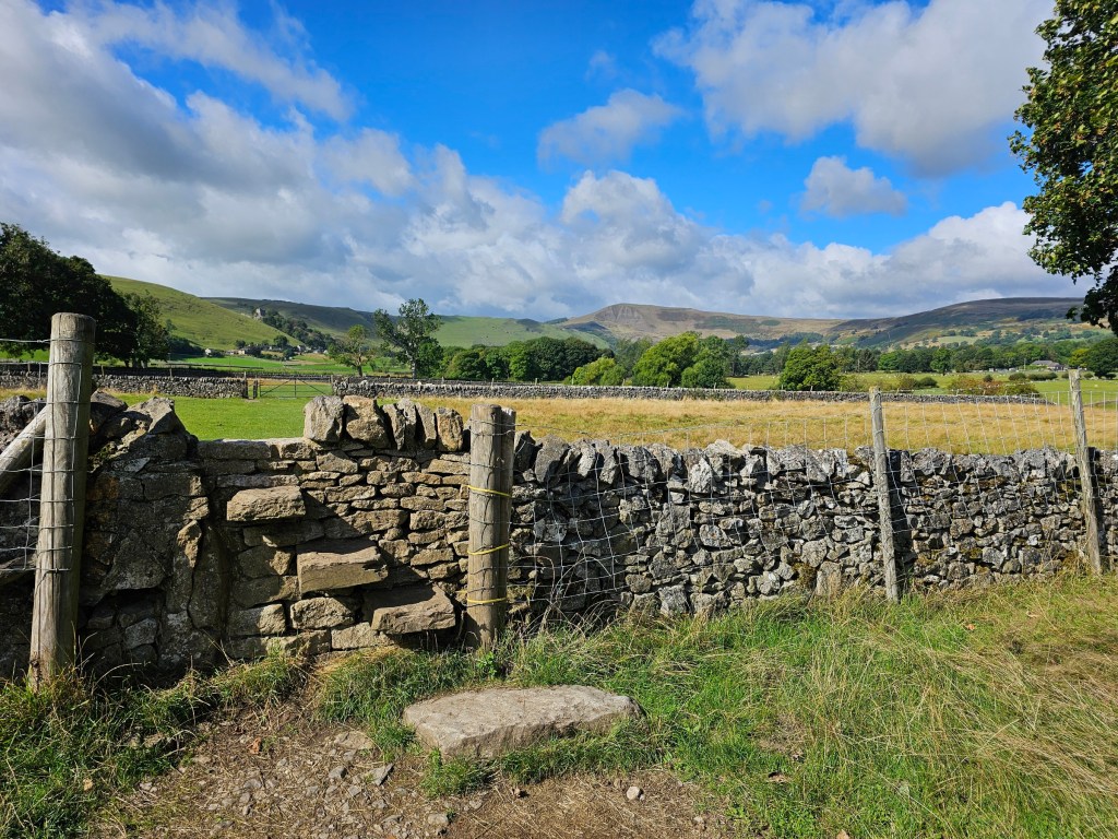 Countryside path from Hope to Castleton in Peak District. There are steps built into the stone fence to allow climbing over it.