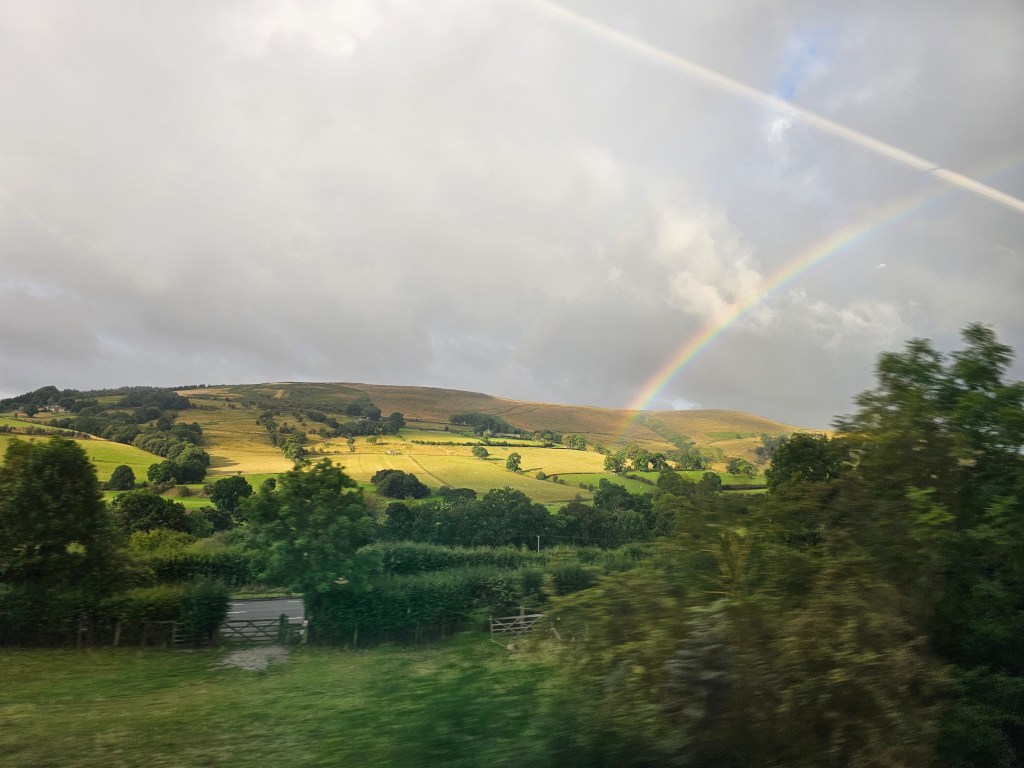 Rainbow seen over the hills of Peak District. Photo taken from a train