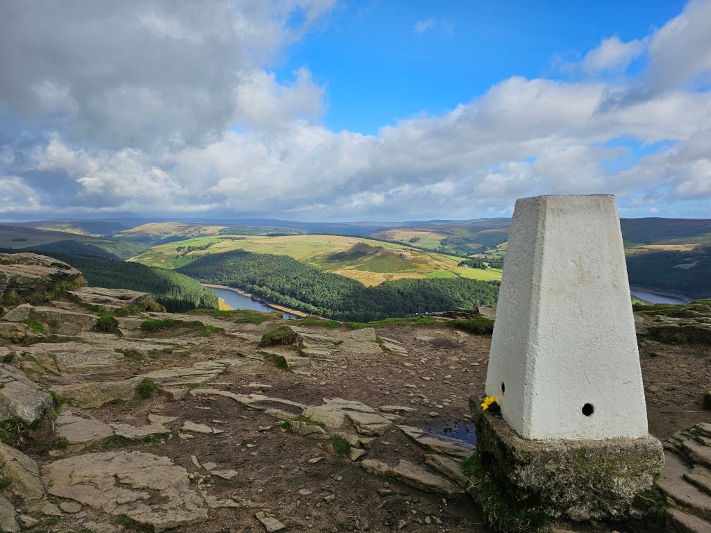 The top of Winn Hill in Peak District, with interesting rock formations and the trig point. Other hills can be seen all around.