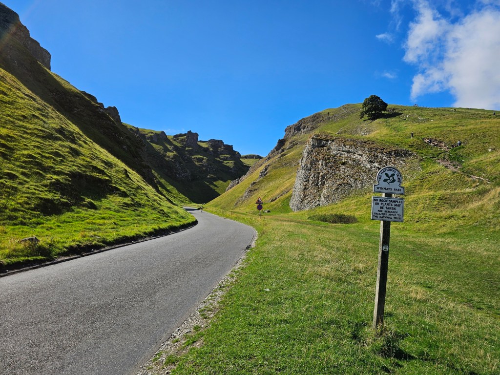 Winnats Pass in Peak District. An asphalt road cutting through the hills.